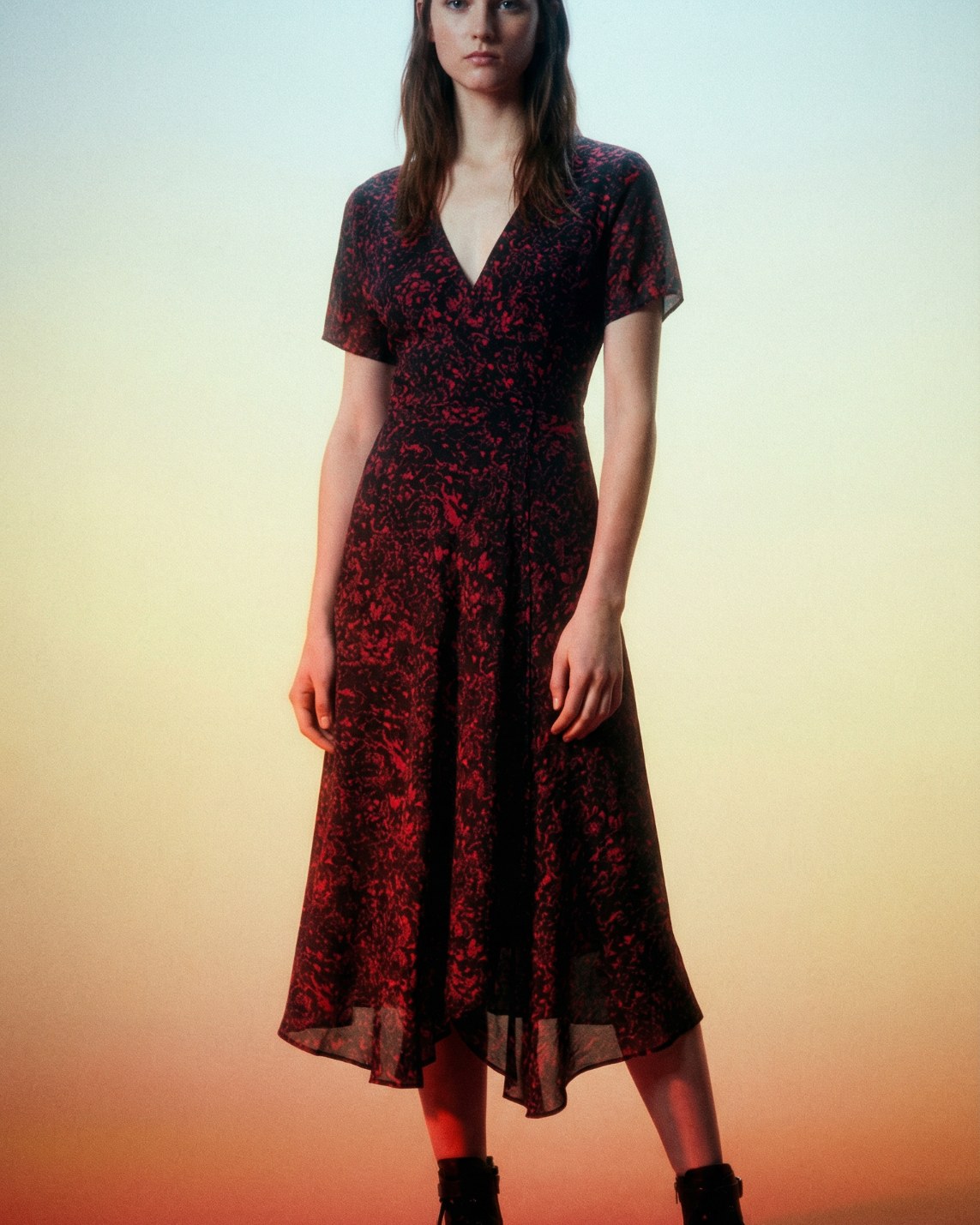 Model wearing a black wrap dress with red floral print and short sleeves