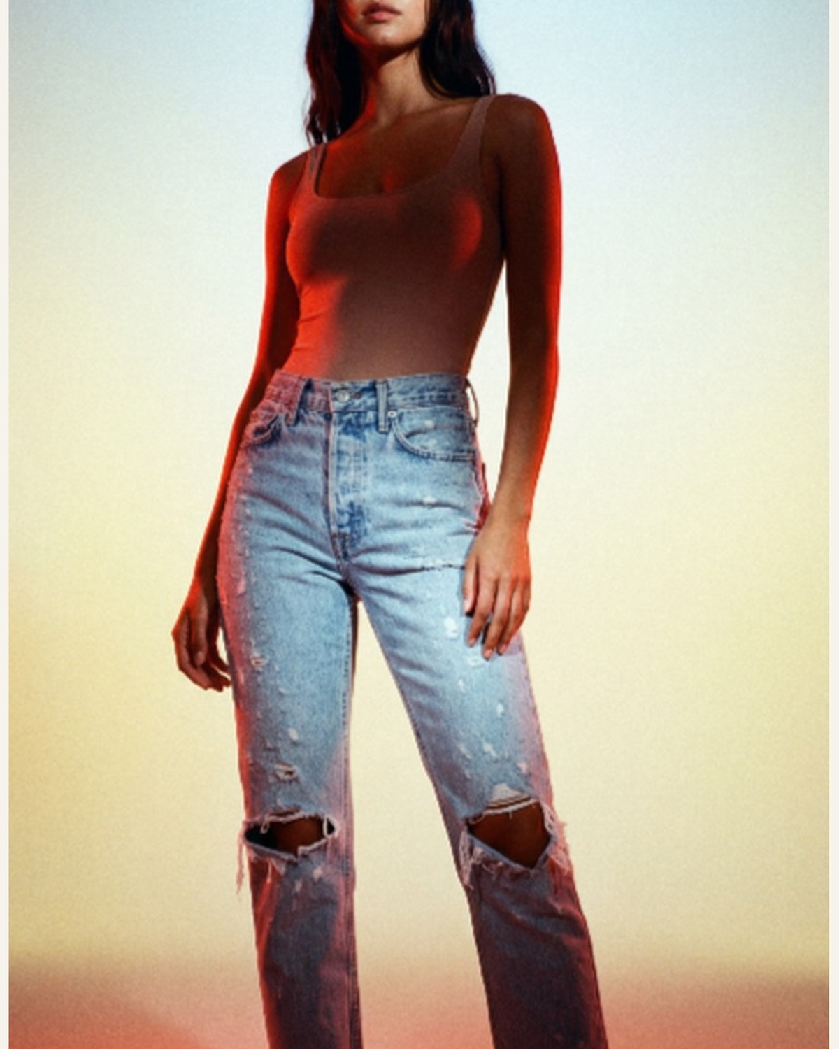 Model wearing distressed high-waist straight-leg jeans with knee rips and frayed hems